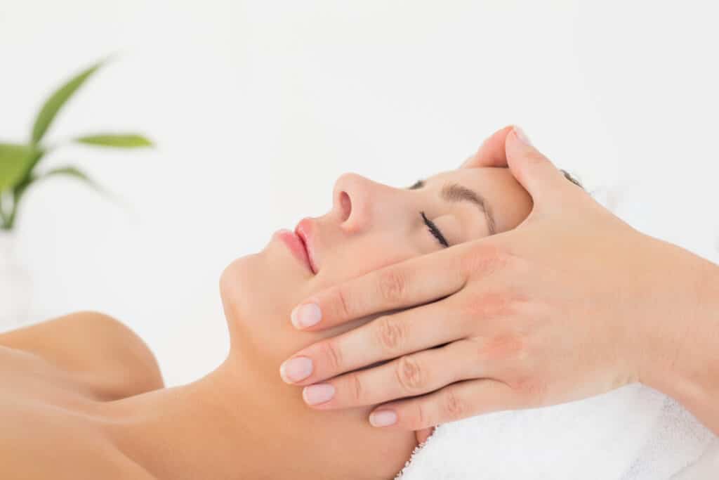 Attractive woman receiving facial massage at spa center
